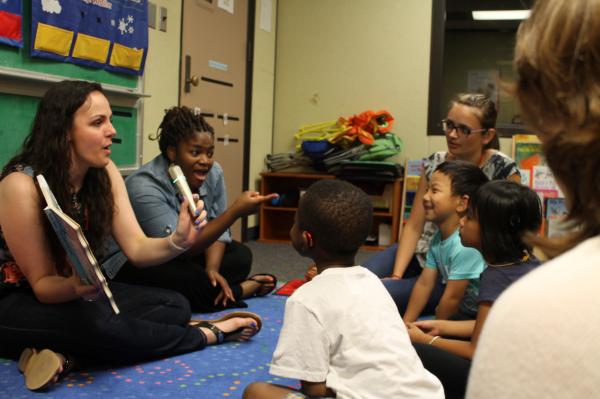 graduate students reading a book to children in HESP summer camp