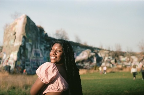 Yewande smiling over her shoulder in front of unique rock formation.