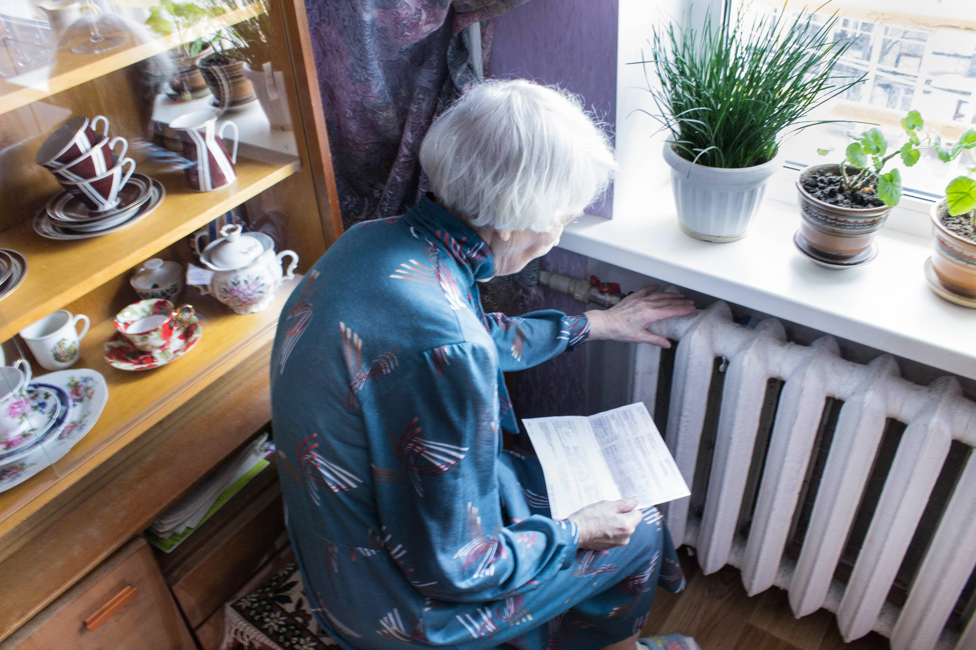 Photo of a senior woman holding an energy bill in front of a radiator is from iStock