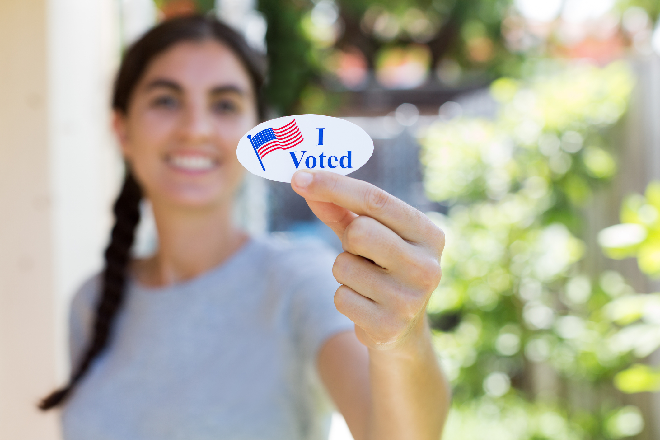 photo of a young woman holding an "I voted" sticker
