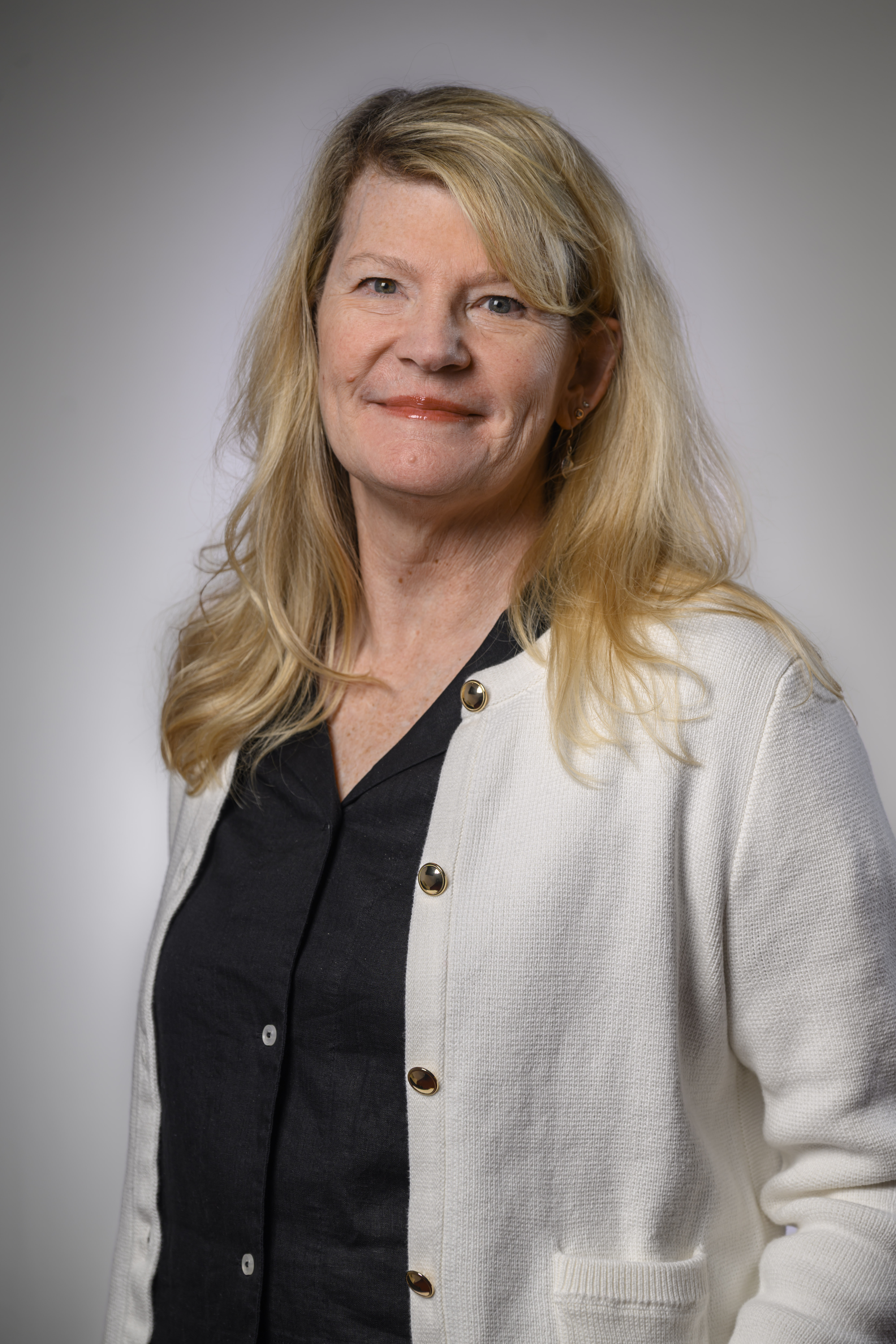 Professional headshot photo of Karen Albert, an alumna of the BSOS Department of Sociology, wearing a black shirt and white sweater