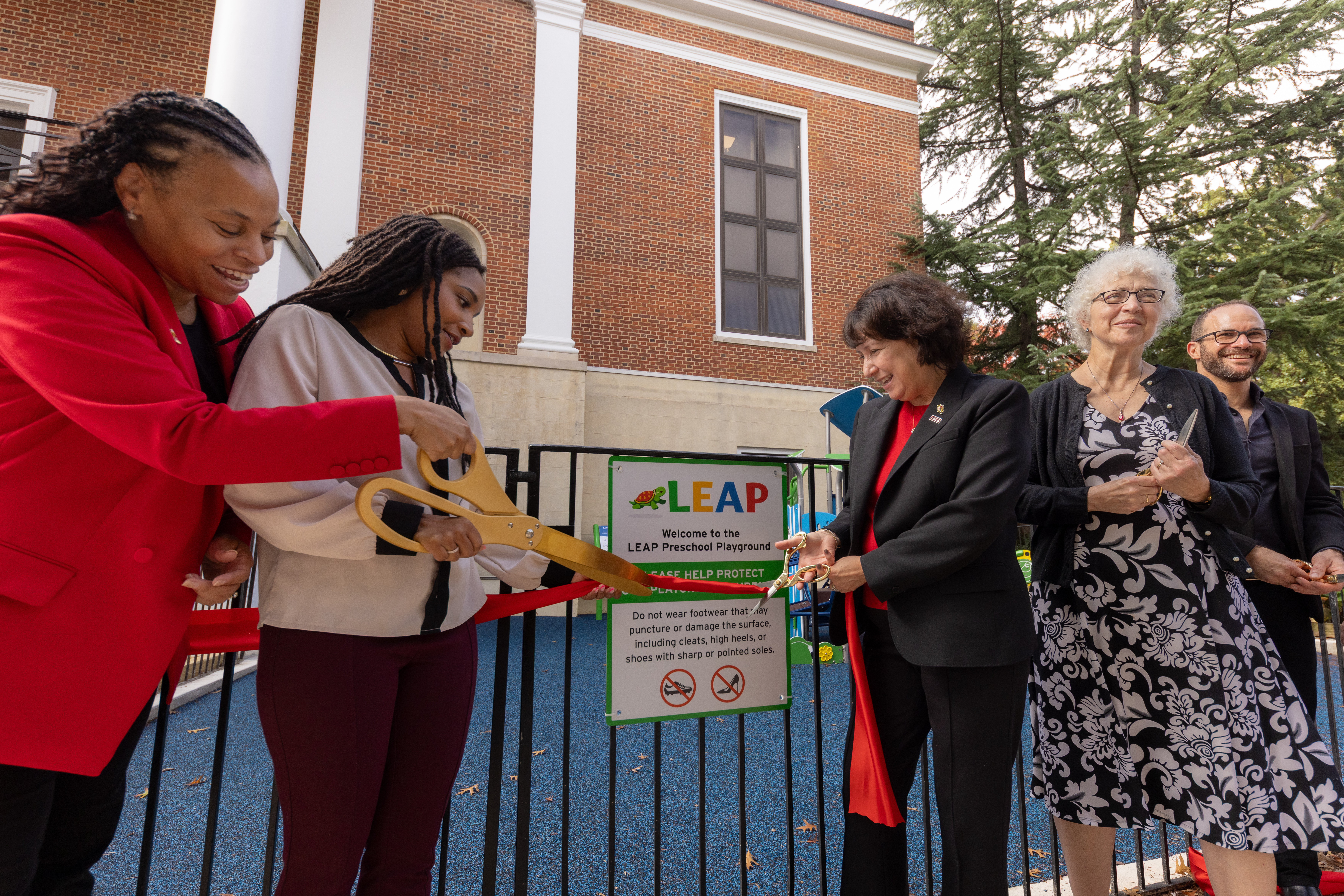UMD BSOS Dean Susan Rivera and faculty/staff of the UMD LEAP program cutting a ribbon in front of the new LEAP playground