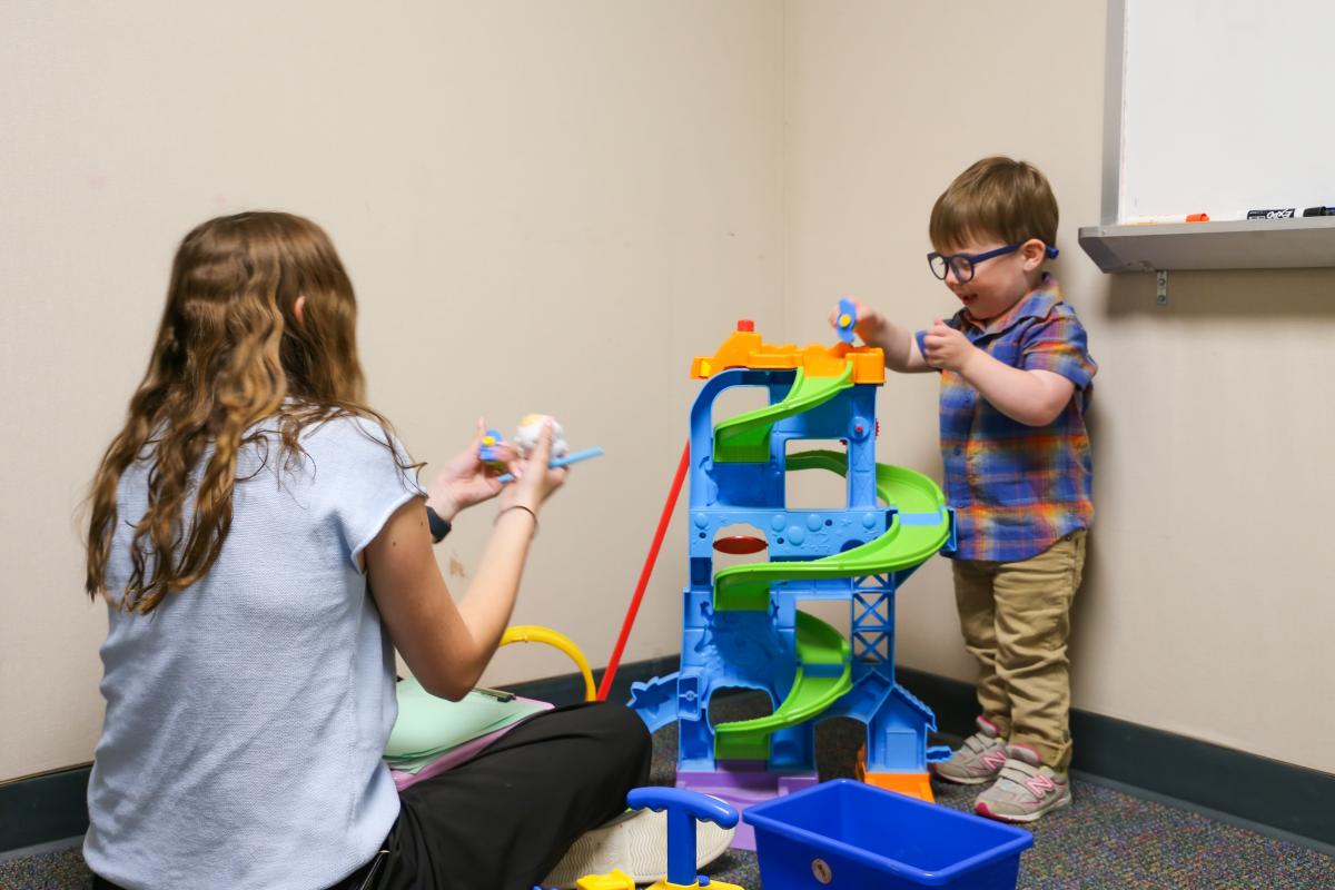 A therapist at the UMD LEAP preschool (right) working with a student, Adrien, (left) using a slide toy