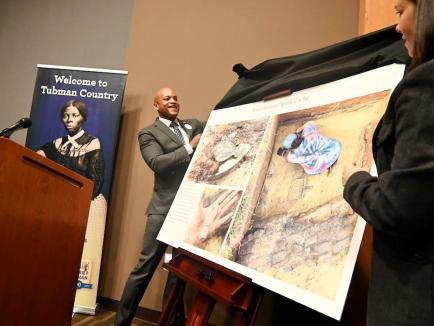 Maryland Gov. Wes Moore and Maryland Department of Transportation Chief Archaeologist Julie Schablitsky, an adjunct assistant professor of anthropology, unveil information about remains of a West African spirit cache found on the former Eastern Shore farm where Harriet Tubman was born at a news conference last month. //Photo by Joe Andrucyk/Maryland GovPics