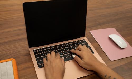 Black hands typing on a laptop