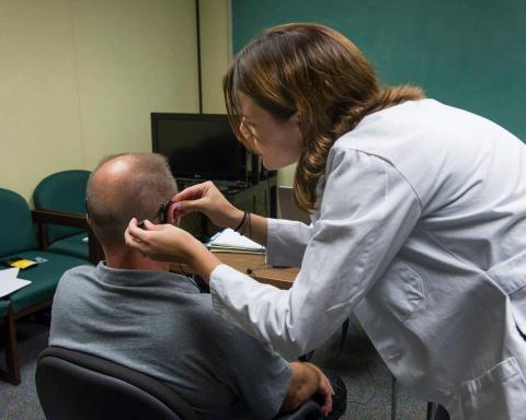 Image of a clinician helping a patient with a hearing aid