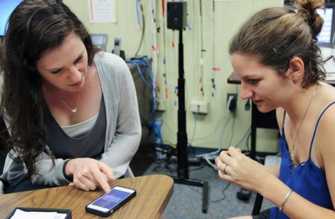 HESP doctoral student Maya Freund helps clinic patient Robyn Bell figure out how to connect her new hearing aides to her iPhone.